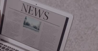 A laptop screen displays a digital newspaper with 