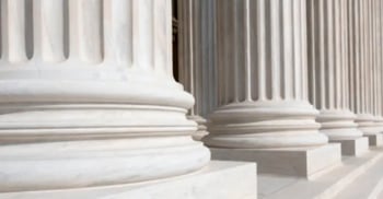 Close-up view of the bases of large, white stone columns on the exterior of a classical-style building.