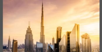Dubai skyline at sunset with a silhouette of modern skyscrapers, including the tallest tower, against a golden sky, conveying a sense of grandeur and innovation.