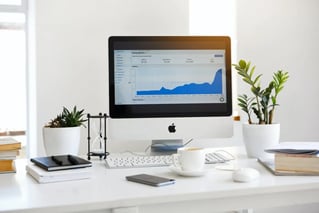 Desktop computer displaying analytics graph on a tidy office desk with plants and books.